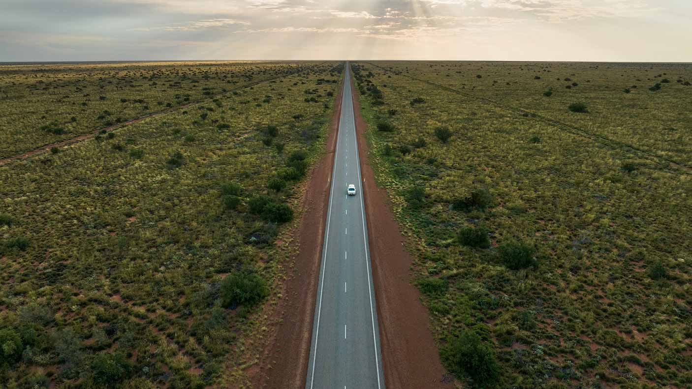 Aerial image showing a camper van driving through the Australian outback on a highway, Western Australia, Australia