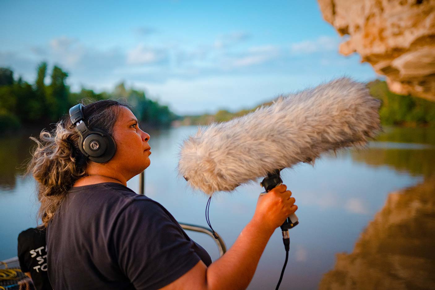 An Aboriginal woman holding a microphone at a lake