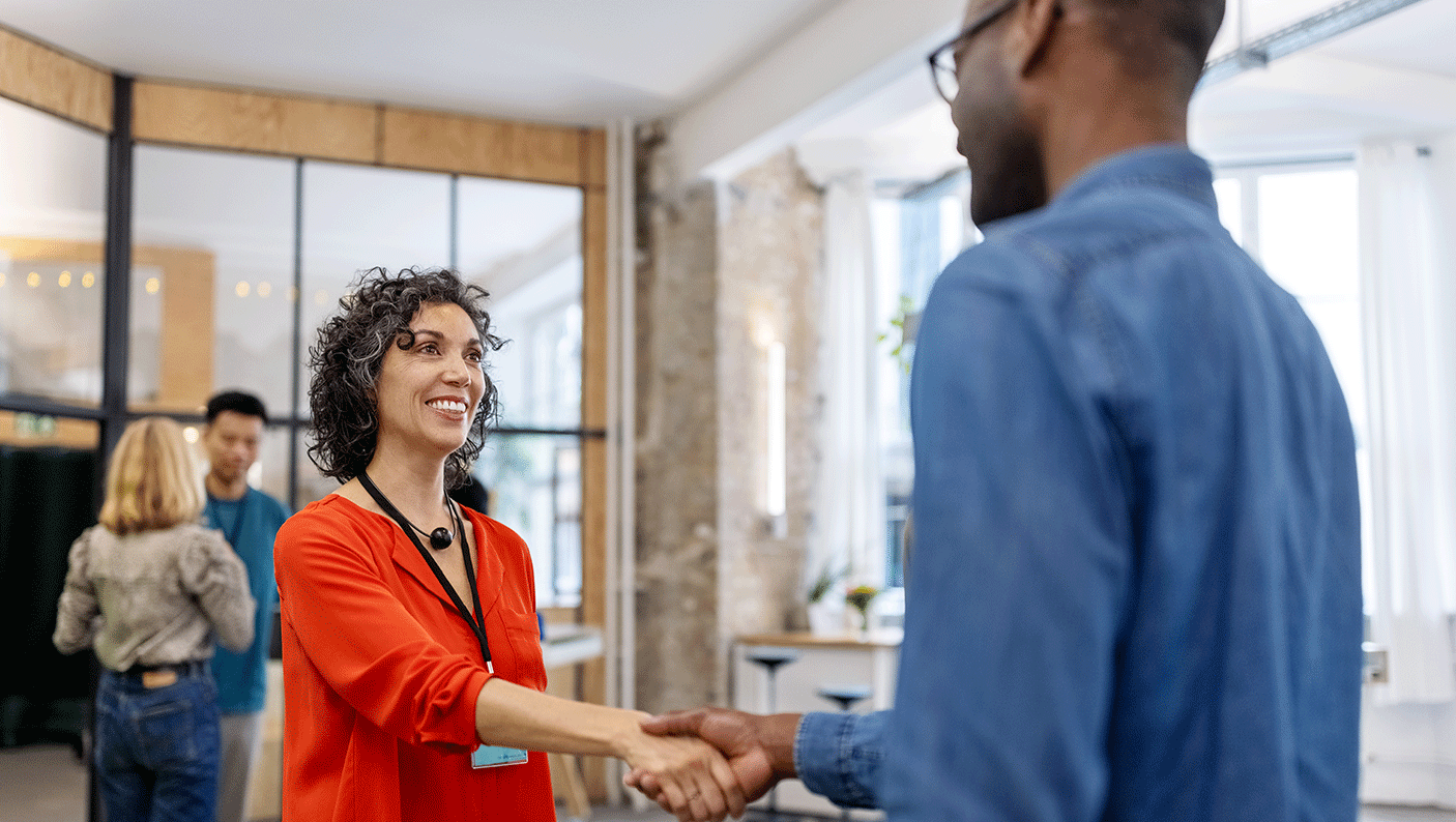 In an office a woman shakes hands with a man