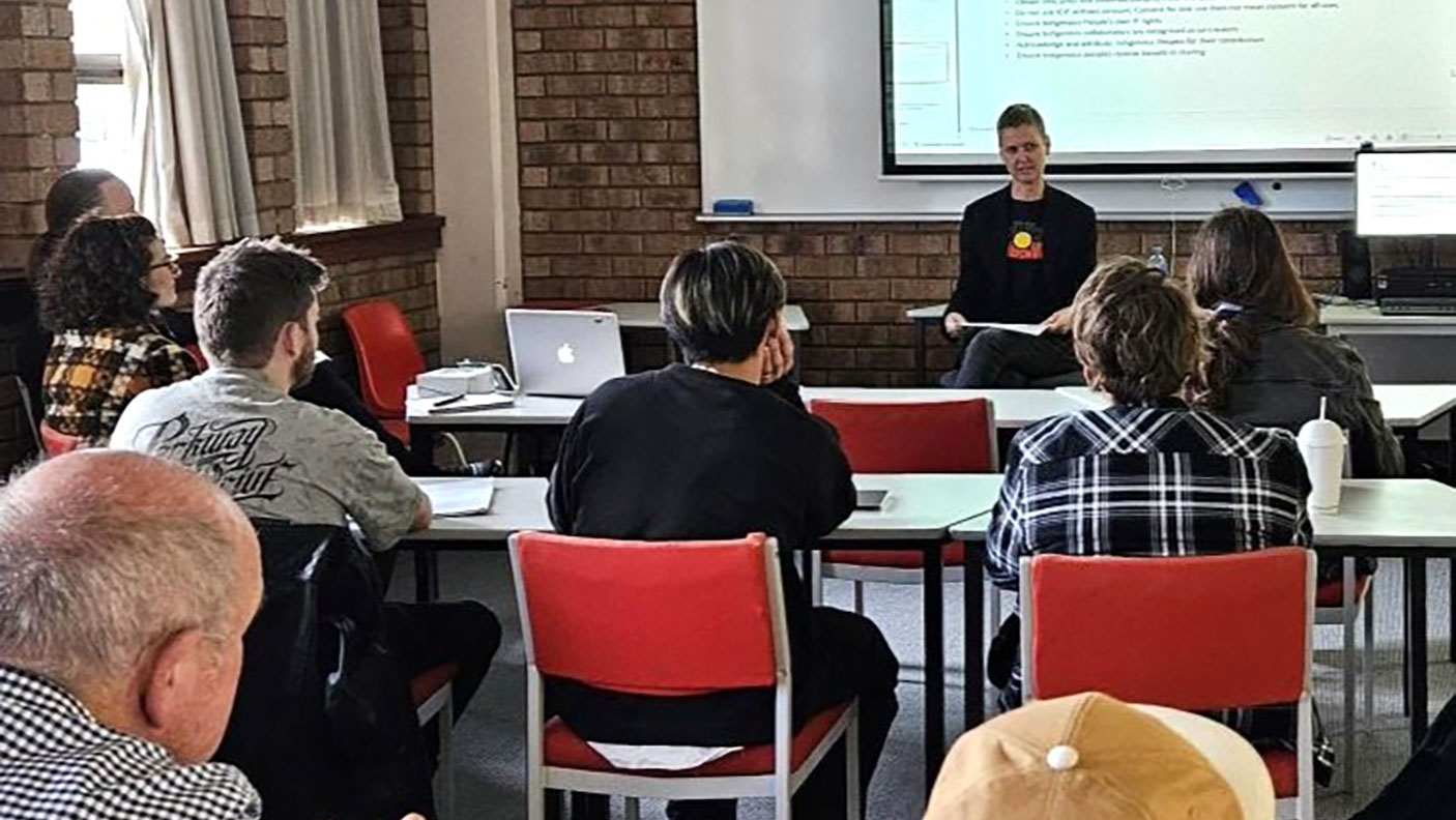 Adults sit in a TAFE classroom watching and listening to a presentation