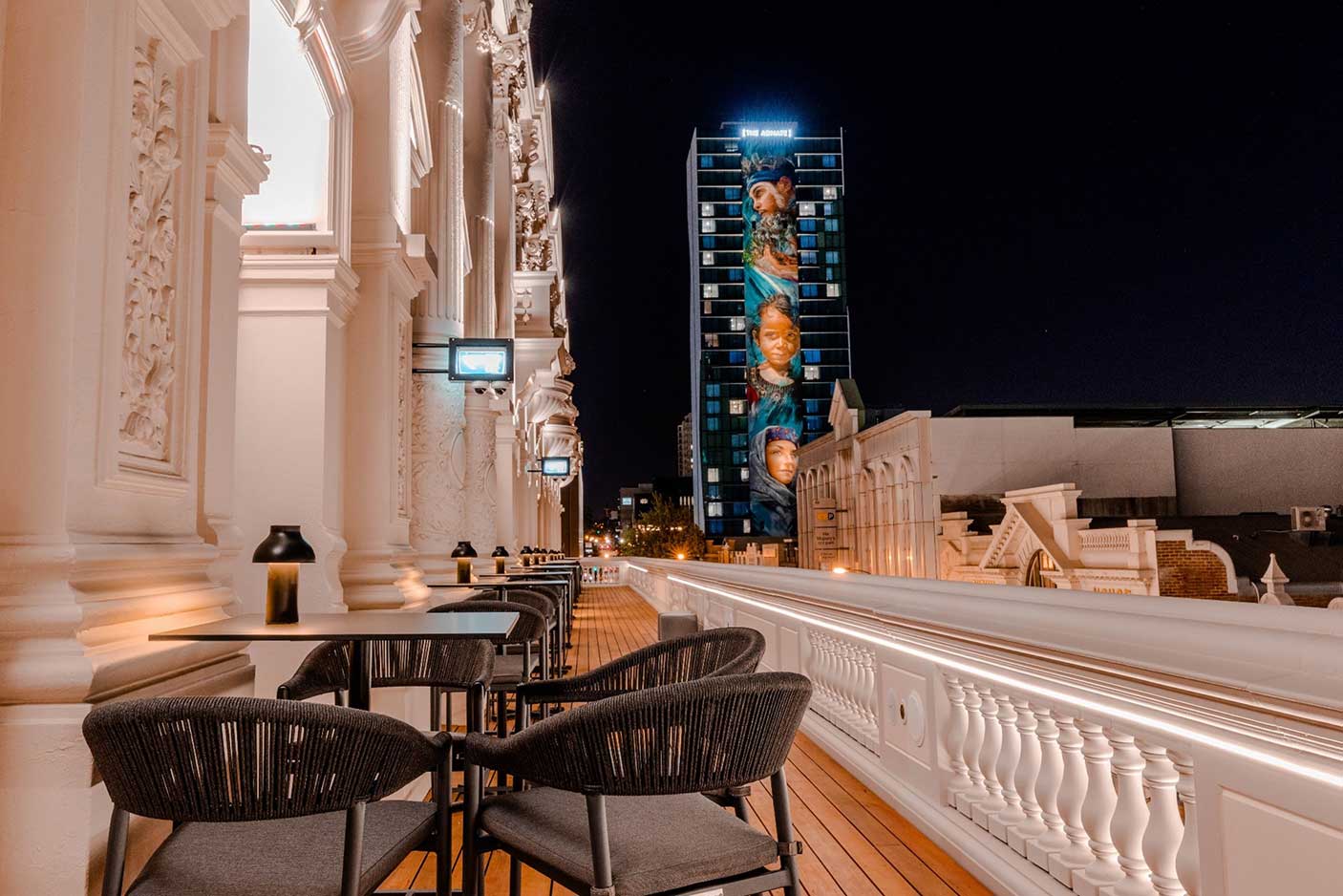 A balcony with tables and chairs at night.