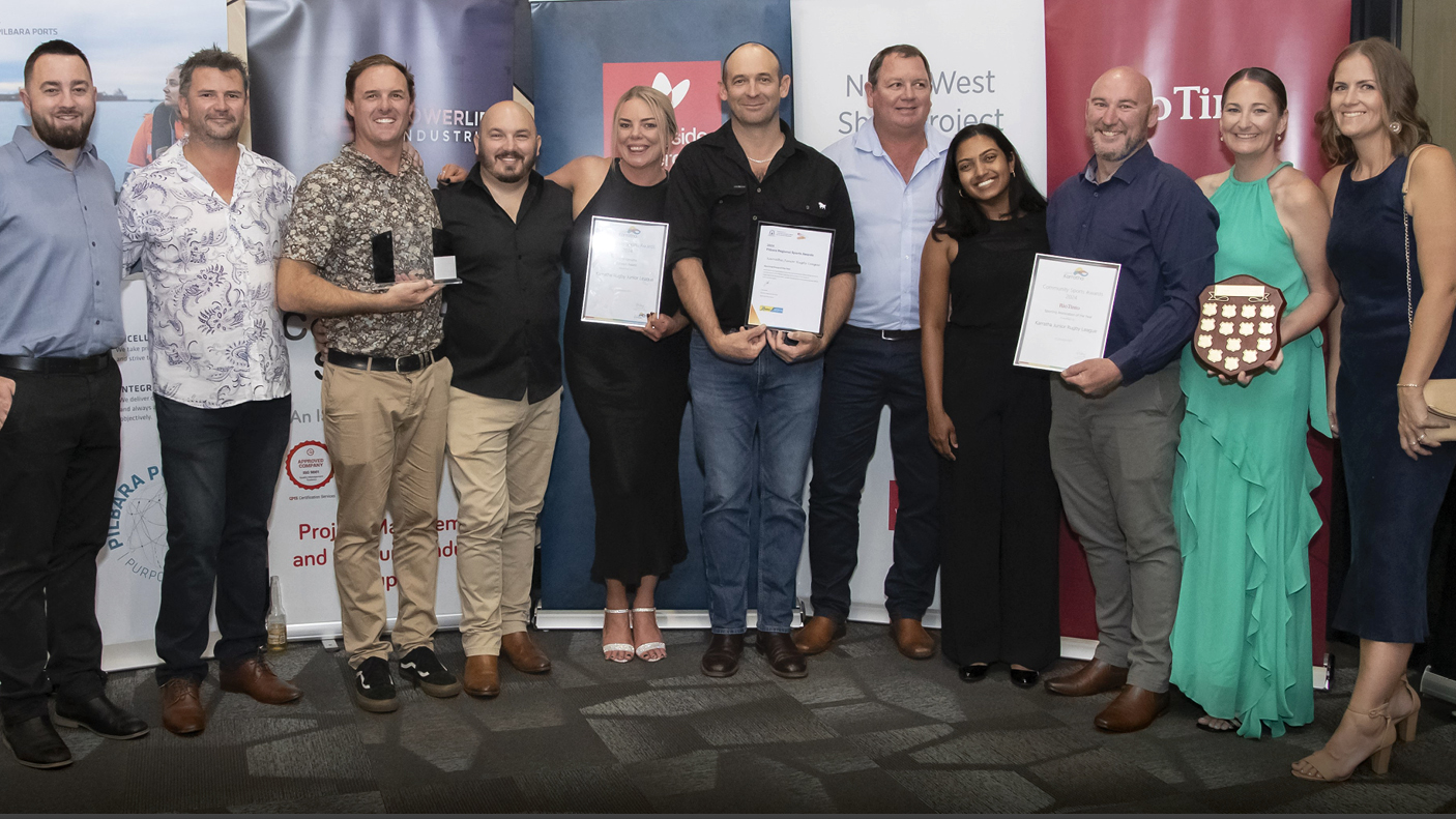 11 people with awards and certificates pose for the camera