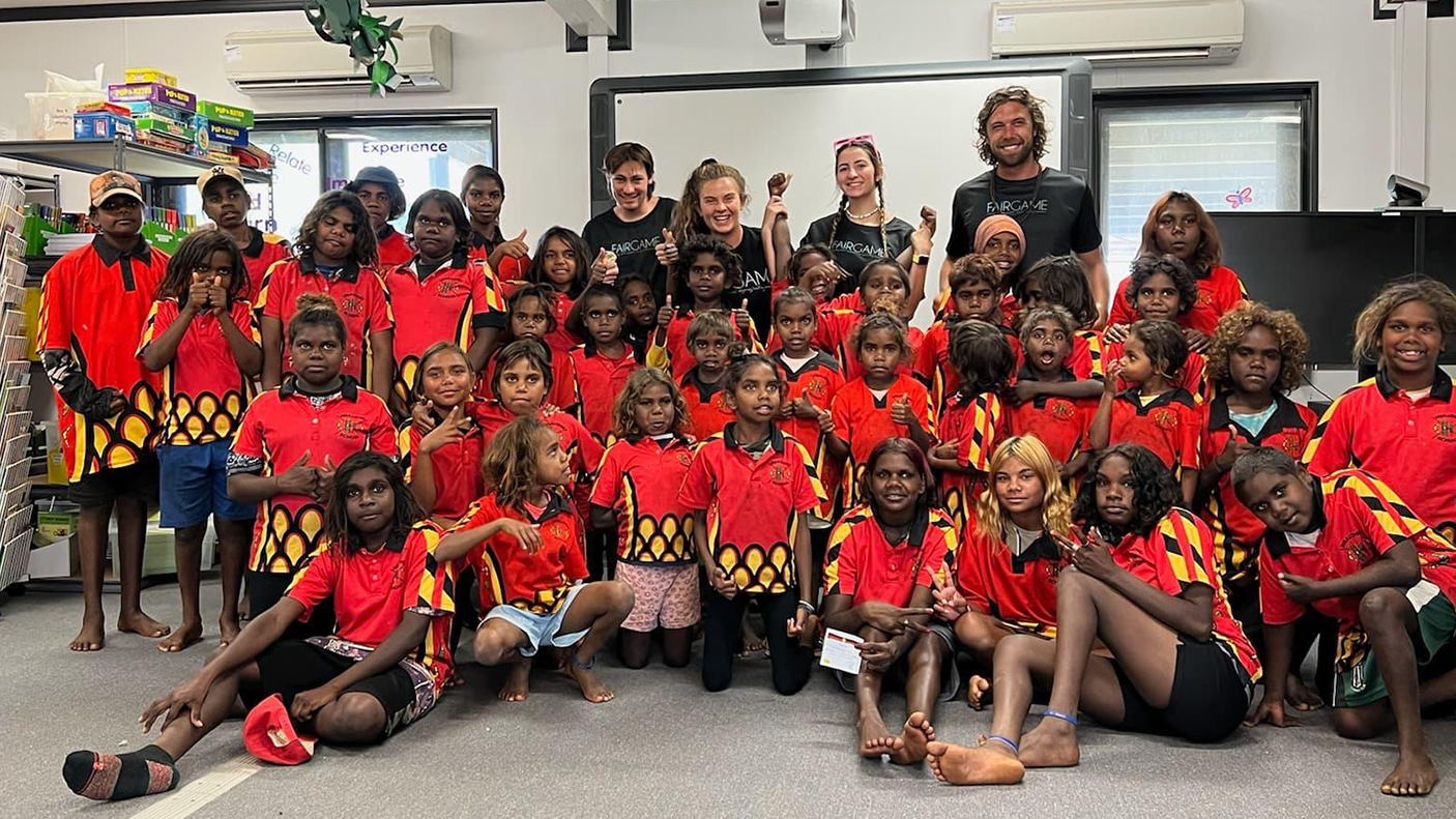 A large group of school children and 4 adults pose for the photo.