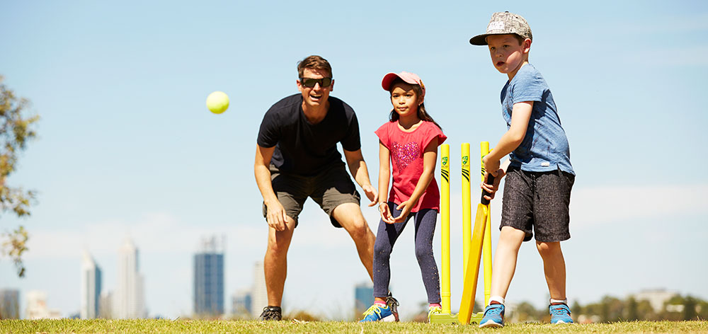 Family and friends playing cricket in the park