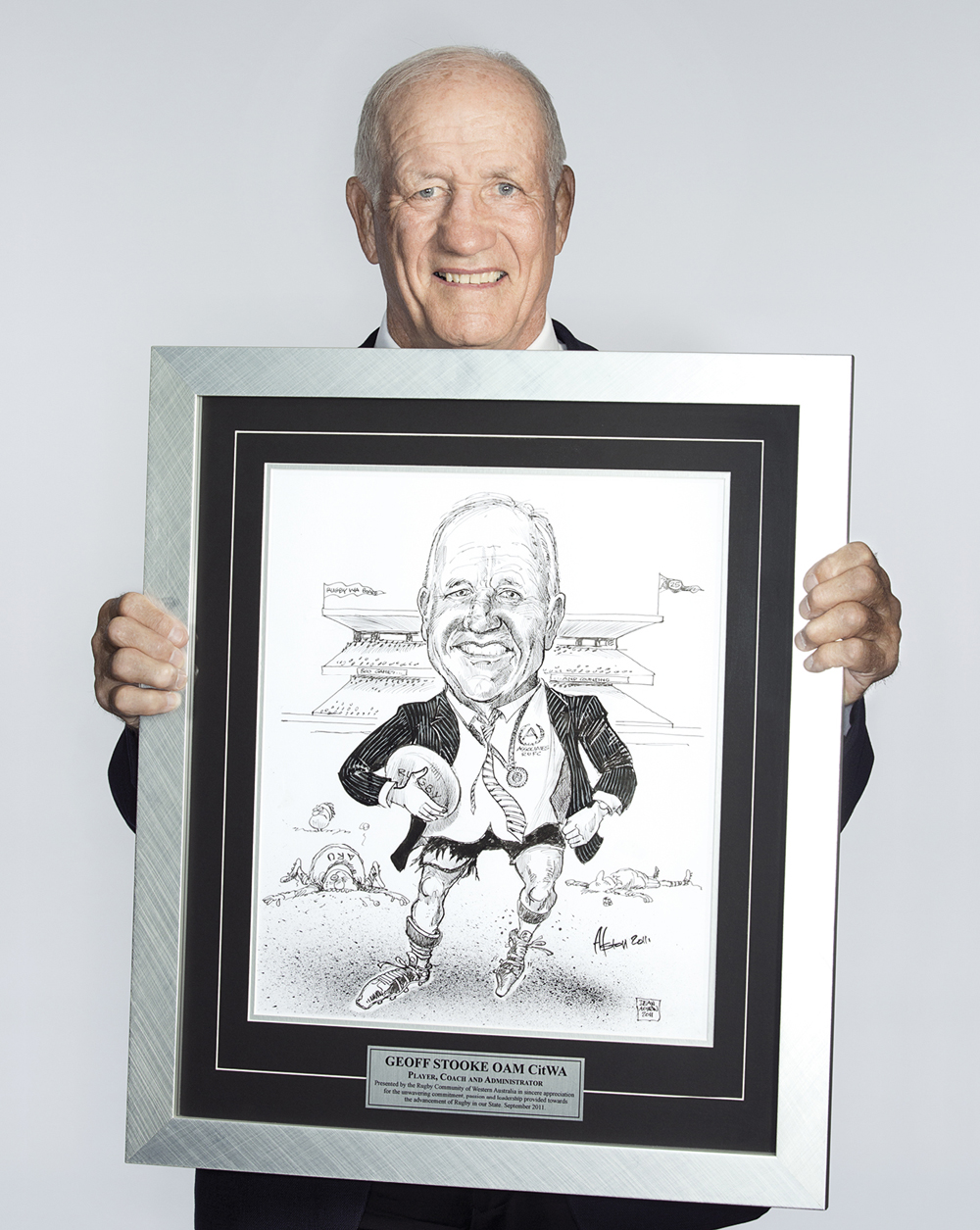 Portrait of Geoffrey Stooke holding a caricature