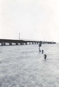 Black and white photo of the jetty with people in the water