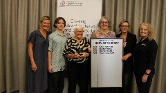 Alice Rule holding the honour board with her name on it. She is with 4 family members and a DLGSC staff member